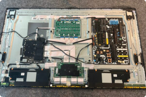 Inside view of a modern television showing power supply, main board, and T-Con board during in-home TV repair.
